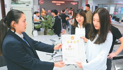 河北省承德市網(wǎng)絡(luò)代購(gòu)經(jīng)營(yíng)者陳晨(右)從工作人員手中接過(guò)帶有統(tǒng)一社會(huì)信用代碼的營(yíng)業(yè)執(zhí)照。 劉環(huán)宇攝(人民圖片)