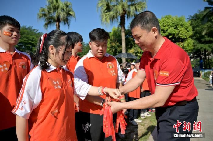 資料圖：廣西華僑實(shí)驗(yàn)高中的教師為高三學(xué)子系上紅絲帶，盼望學(xué)子高考必勝。 俞靖 攝